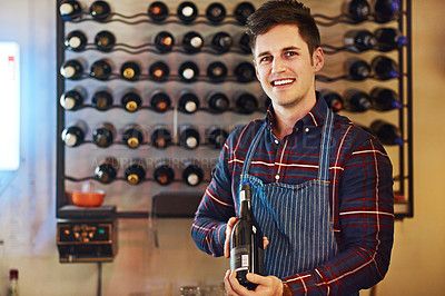 Buy stock photo Shot of a handsome young man choosing a bottle of wine in a restaurant