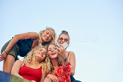 Buy stock photo Low angle shot of a group of attractive young girlfriends taking selfies in the city