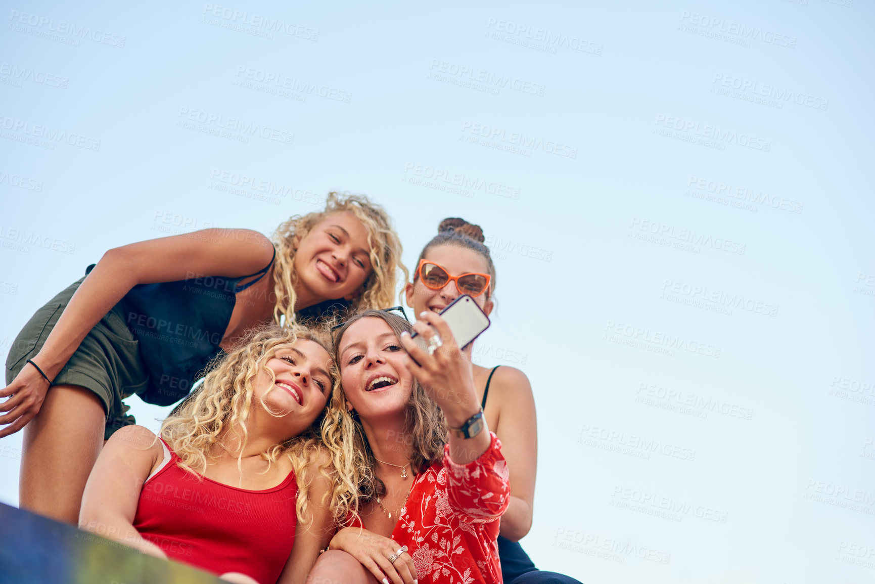 Buy stock photo Low angle shot of a group of attractive young girlfriends taking selfies in the city