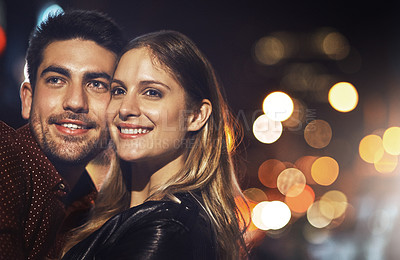 Buy stock photo Shot of a happy young couple standing together outside at night