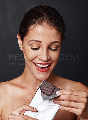 Buy stock photo Happy woman, dessert and chocolate in studio eating for unhealthy food, sugar craving or cheat meal on dark background. Smile, diet and model for snack temptation, sweet addiction or cacao bar