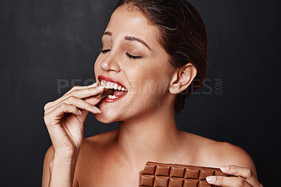 Buy stock photo Happy, woman and eating with chocolate in studio for temptation of unhealthy snack. Female person,  biting and dessert with cocoa treat for calories, sugar and nutrition for health of diabetes
