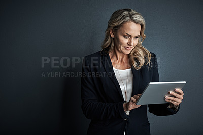 Buy stock photo Studio shot of a mature businesswoman using a digital tablet against a grey background