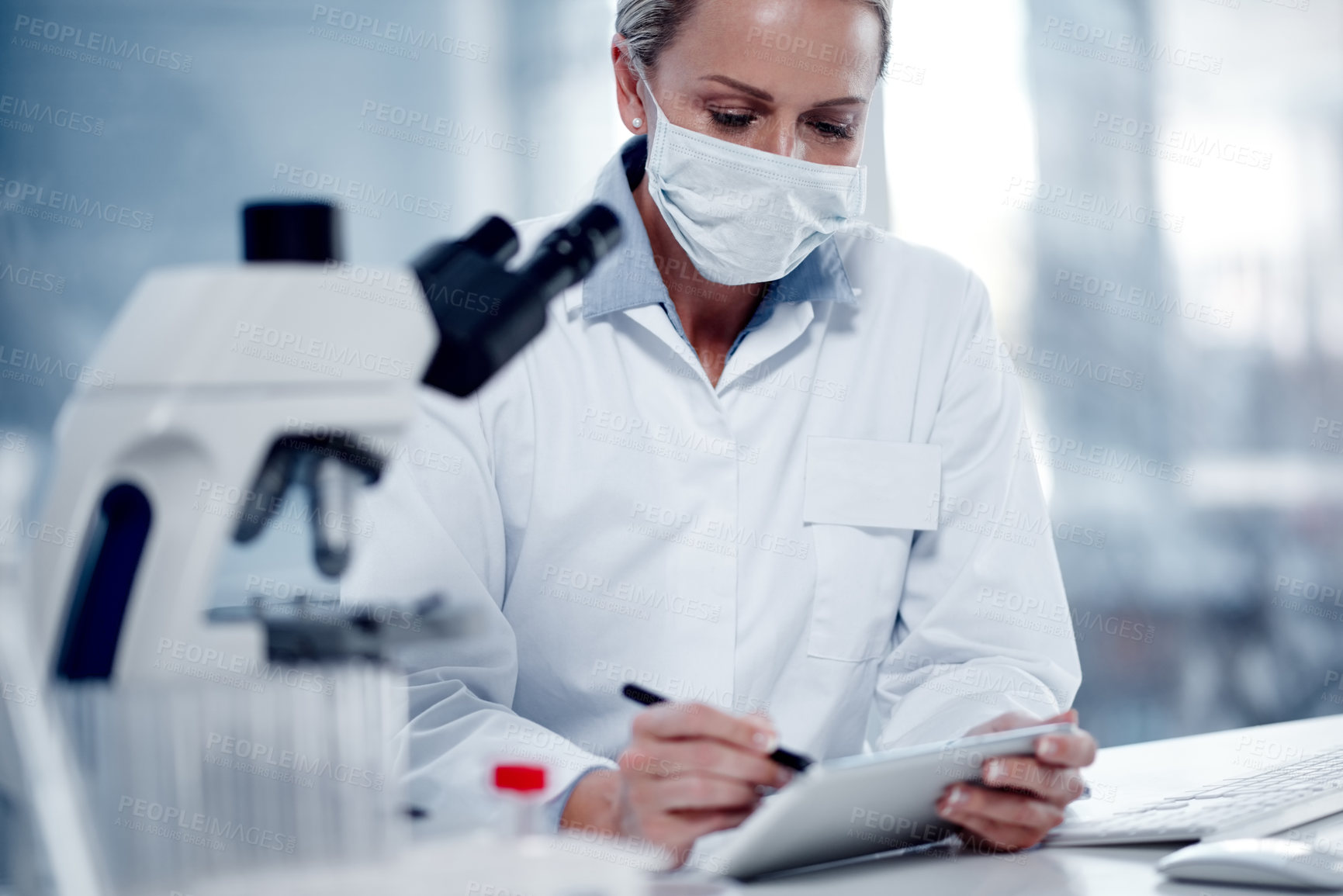 Buy stock photo Shot of a mature scientist using a digital tablet while working in her lab