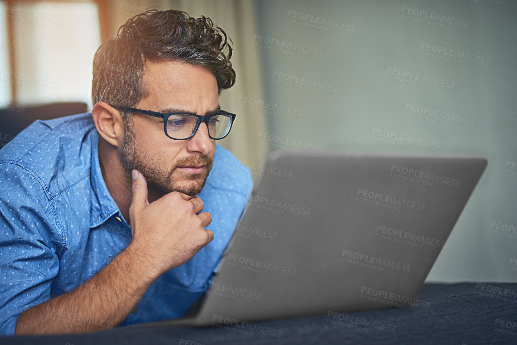 Buy stock photo Serious, man and relax with laptop in home for streaming service, website and watching online movie. Male person, glasses and thinking with tech in house for internet, connectivity and digital film