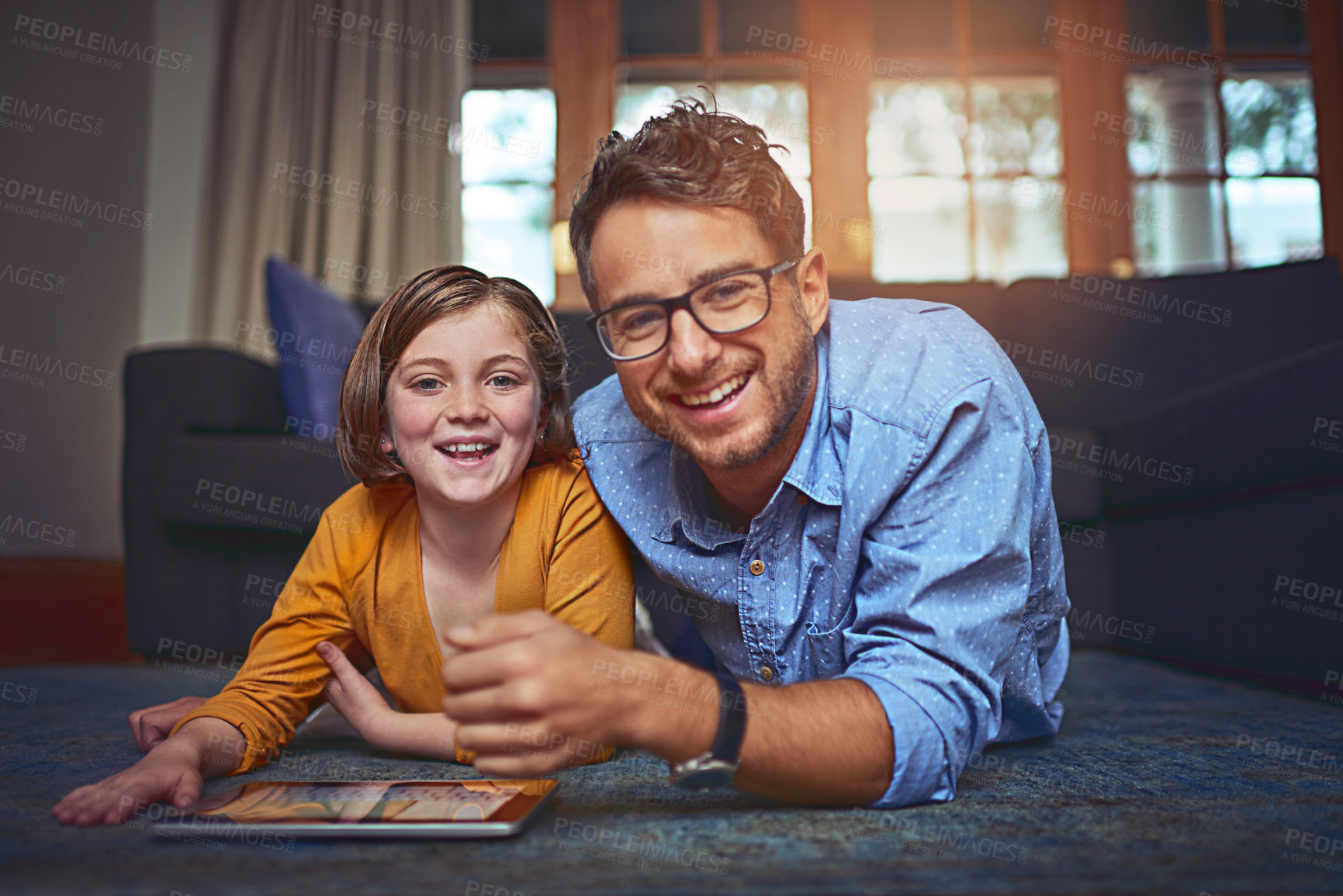 Buy stock photo Shot of a father and daughter lying on the floor and using a digital tablet together at home