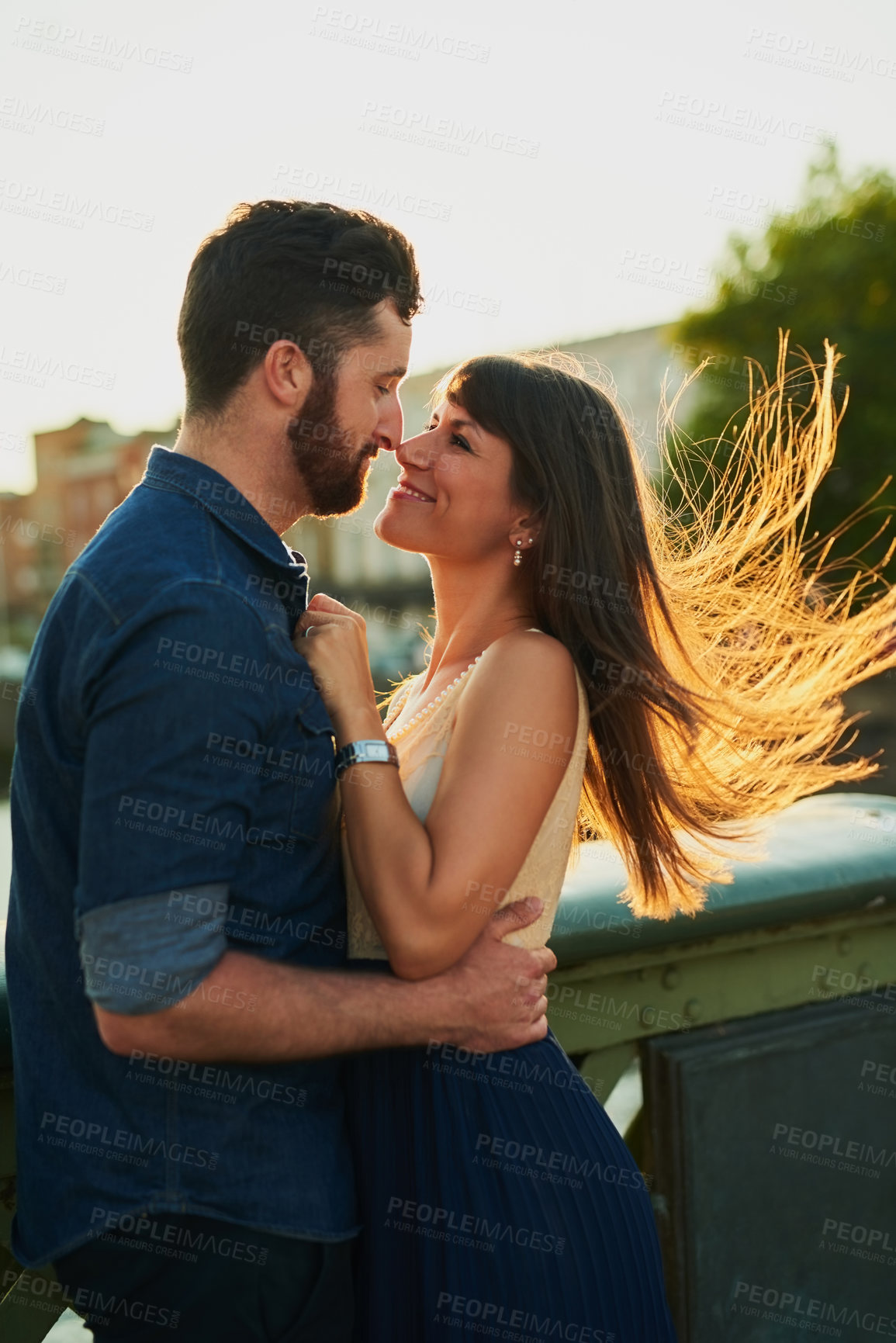 Buy stock photo Couple, smile and hug with love in city for romantic outdoor date, vacation and holiday together. Man, woman and kiss in romance with connection at sunset for weekend adventure, embrace and marriage