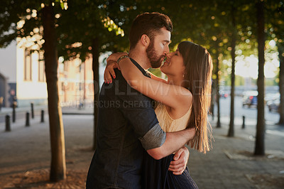 Buy stock photo Kissing, care and couple with hug in nature for romance, connection and happiness together. Love, embracing and young people with bonding for sweet moment, commitment or marriage outdoor in city.