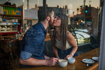 Buy stock photo Coffee shop, happy and couple kiss for love with drink, caffeine beverage and cappuccino in cafe. Dating, window and man and woman relax in restaurant for bonding, relationship and romance on weekend