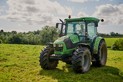 Buy stock photo Man, farm and green tractor on grass in countryside for agriculture, lawn or sustainability in nature. Male person or farmer in big agricultural machinery for farming, ecology or construction on land