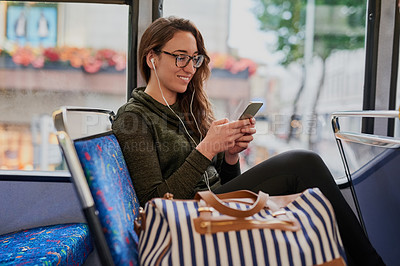 Buy stock photo High angle shot of an attractive young woman listening to music while sitting on a bus
