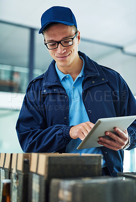 Buy stock photo Shot of a courier using a digital tablet while sorting through boxes for delivery