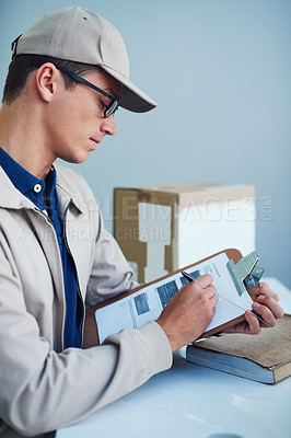 Buy stock photo Shot of a courier writing on a clipboard