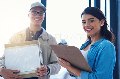 Buy stock photo Portrait of a young woman signing for a delivery from the courier