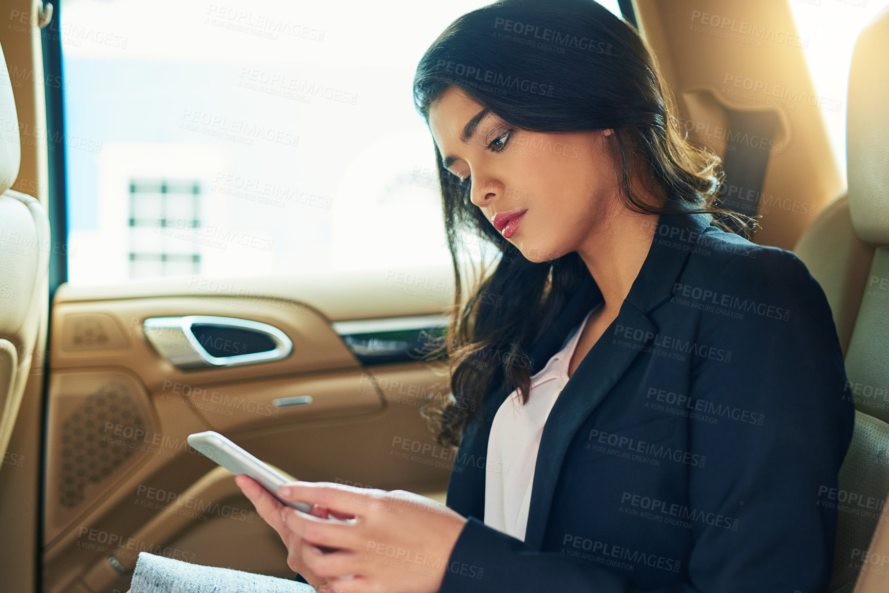 Buy stock photo Shot of an attractive young businesswoman using a cellphone in a car