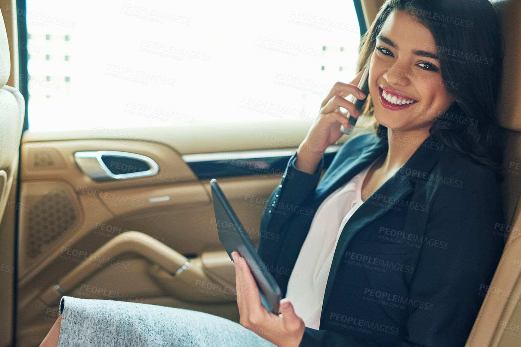 Buy stock photo Shot of an attractive young businesswoman on call while using a tablet in a car