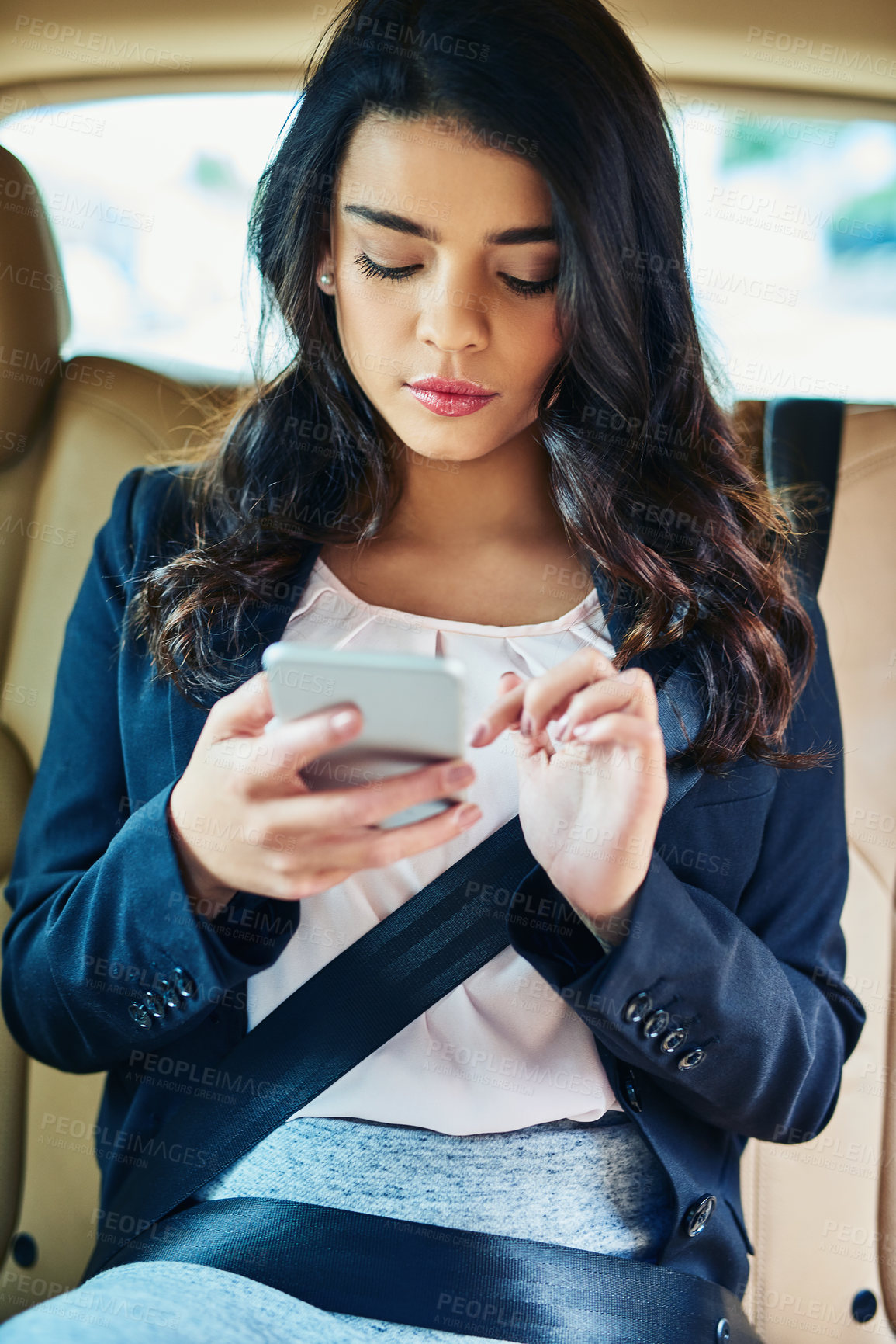 Buy stock photo Shot of an attractive young woman using a cellphone in a car