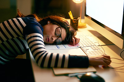 Buy stock photo Shot of a young businesswoman sleeping on her desk while working late in an office