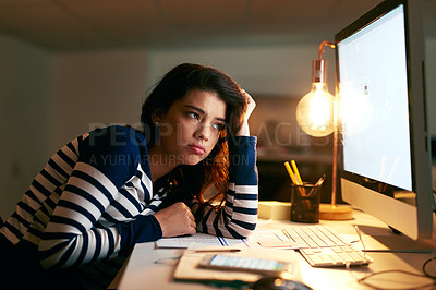 Buy stock photo Shot of a young businesswoman looking bored while working late in an office
