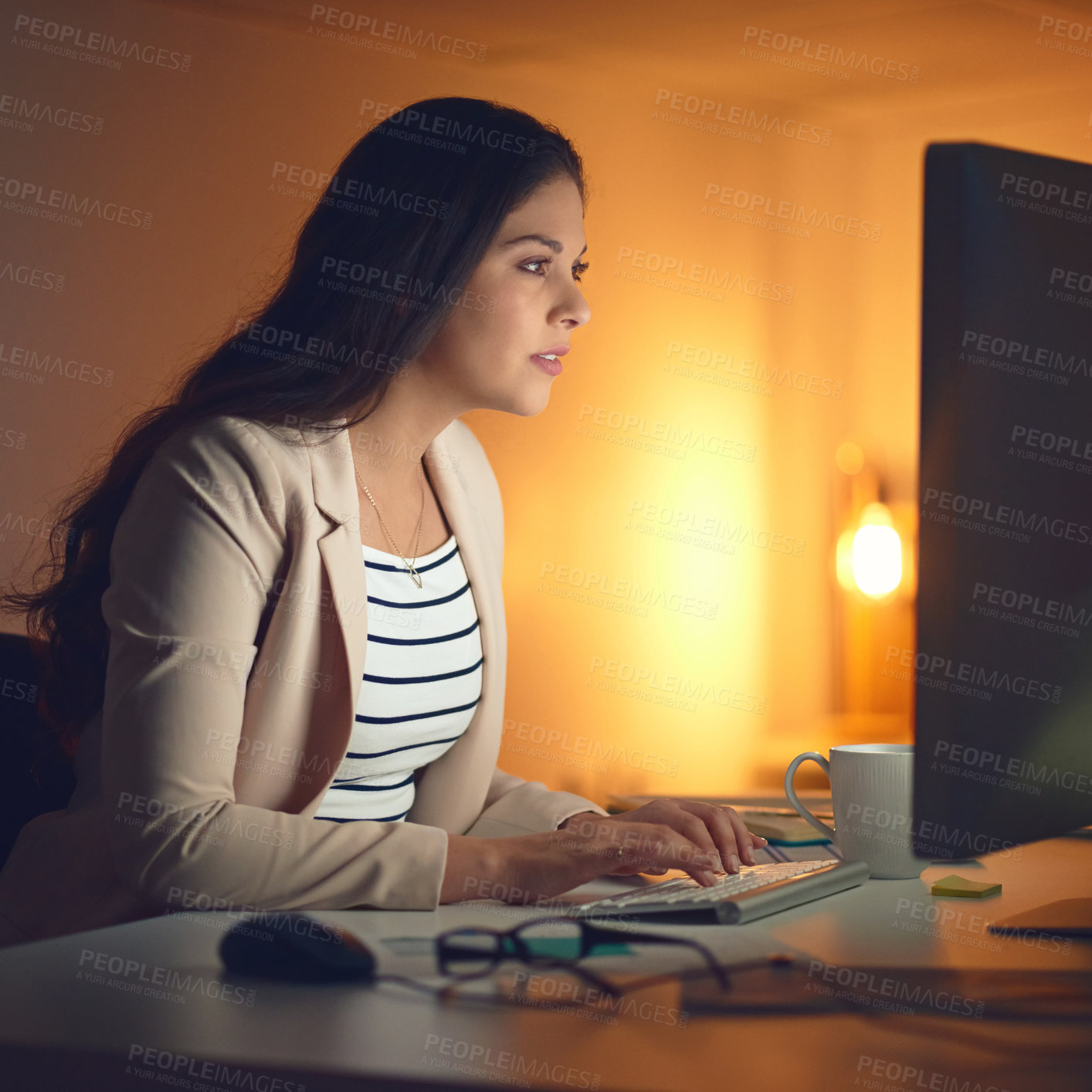 Buy stock photo Shot of a young businesswoman using a computer during a late night at work