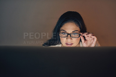 Buy stock photo Shot of a young businesswoman using a computer during a late night at work