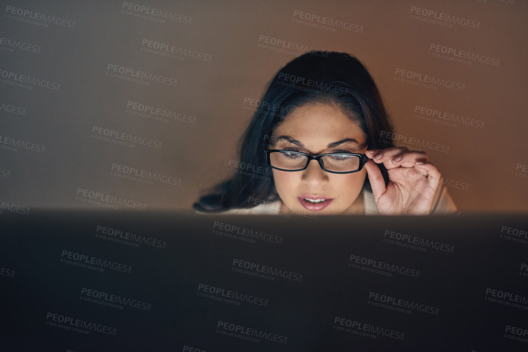 Buy stock photo Shot of a young businesswoman using a computer during a late night at work