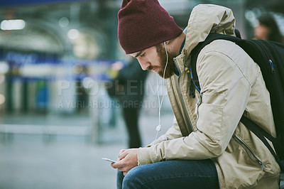 Buy stock photo Travel, city and man with phone at station for music, streaming subscription and radio. Urban town, train commute and person on smartphone with earphones for listening to song, audio and podcast