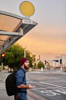 Buy stock photo Man, phone and listen to music at bus station, outdoor travel and waiting for public transport. Male person, online streaming and earphones in urban city, New York traveler and journey commute delay