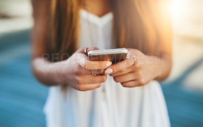 Buy stock photo Cropped shot of an unrecognizable young woman sending a text message while standing outside