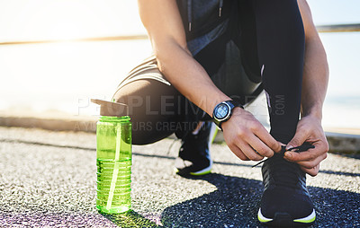 Buy stock photo Closeup shot of an unidentifiable man tying his laces while exercising outdoors