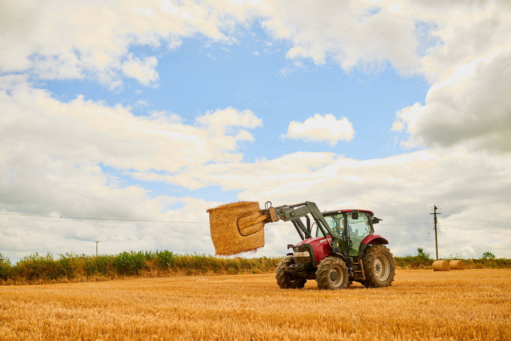 Buy stock photo Straw, agriculture and a tractor on a farm for sustainability on an open field during the spring harvest season. Nature, sky and clouds with a red agricultural vehicle harvesting hay in a countryside