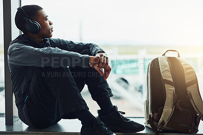 Buy stock photo Shot of a young man listening to music while sitting at the airport waiting for departure