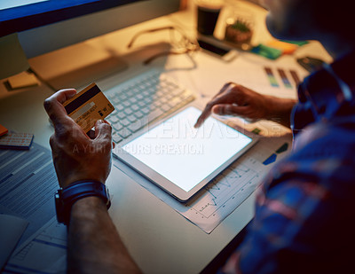 Buy stock photo Cropped shot of an unrecognizable businessman using a credit card and digital tablet during a late night at work