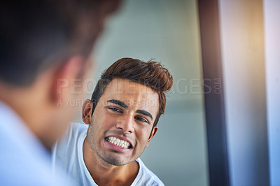 Buy stock photo Shot of a handsome young man admiring his freshly brushed teeth in the bathroom mirror