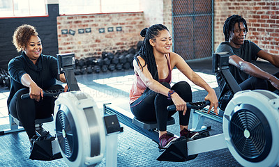 Buy stock photo Shot of a fitness group working out on rowing machines in their session at the gym