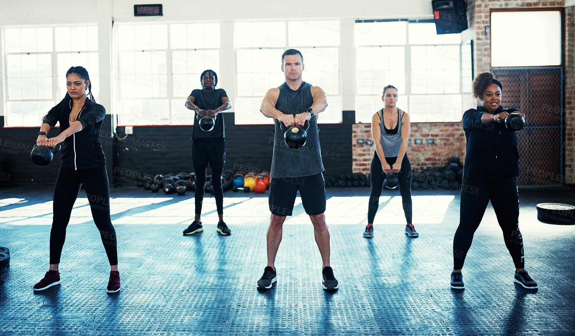 Buy stock photo Shot of a fitness group using kettle-bells in their session at the gym