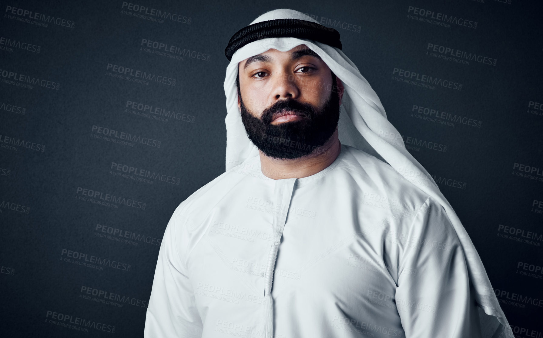 Buy stock photo Studio shot of a young man dressed in Islamic traditional clothing posing against a dark background