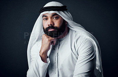 Buy stock photo Studio shot of a young man dressed in Islamic traditional clothing posing against a dark background