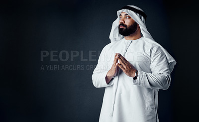 Buy stock photo Studio shot of a young man dressed in Islamic traditional clothing posing against a dark background