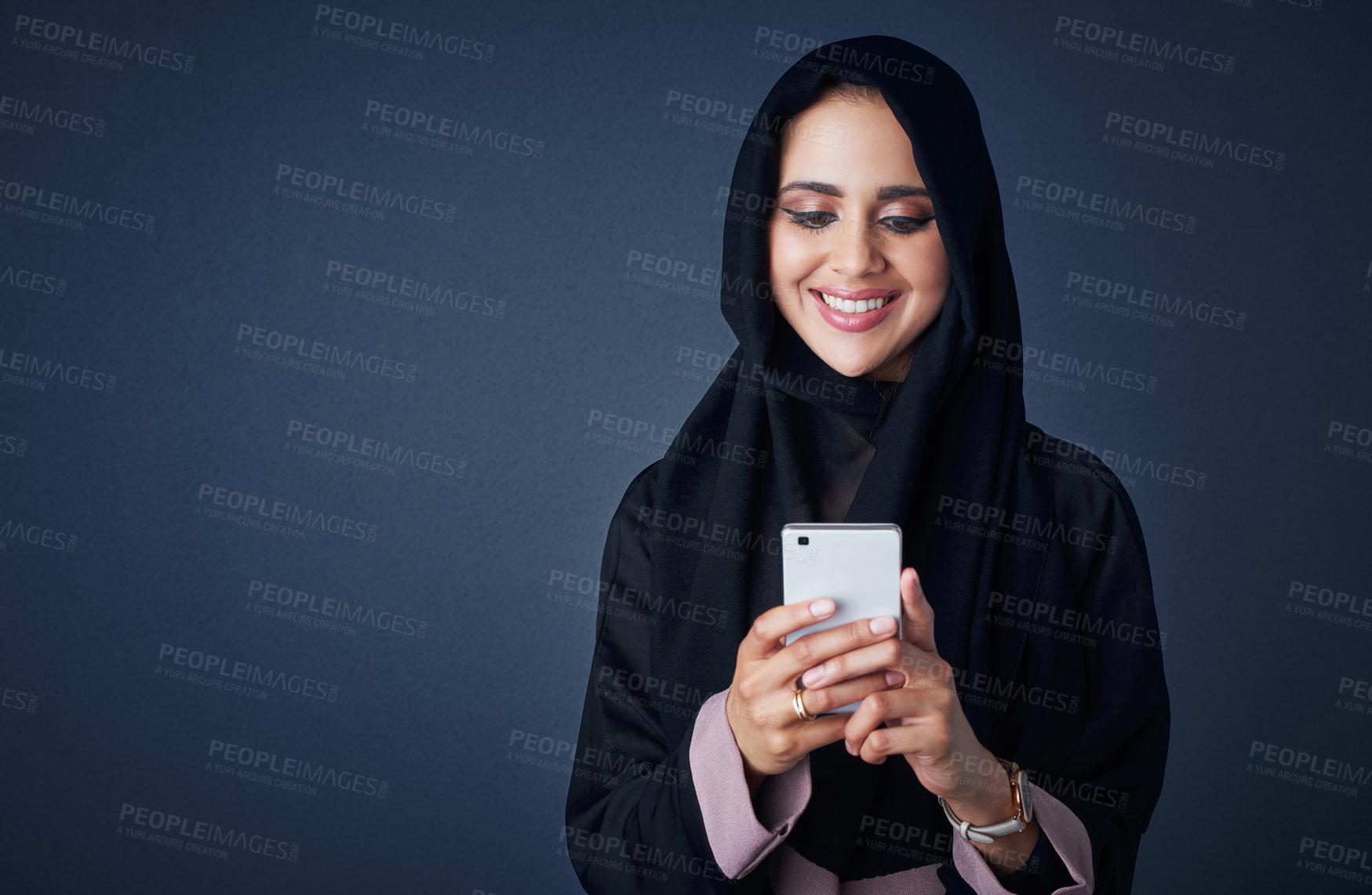 Buy stock photo Studio shot of a young woman wearing a burqa and using a mobile phone against a gray background