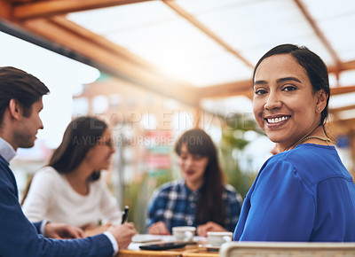 Buy stock photo Portrait of a cheerful young creative businesswoman having a discussion with coworkers at a meeting around a table while looking back at the camera