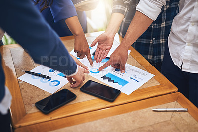Buy stock photo Shot of a group unrecognizable people pointing at chart papers around a table at a coffeeshop