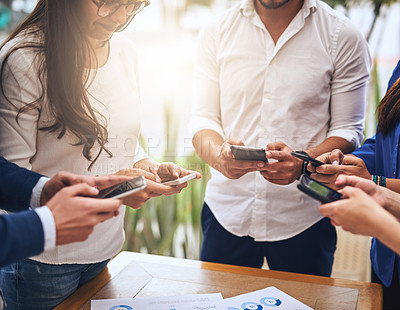 Buy stock photo Shot of a group of unrecognisable work colleagues  standing in a circle and using their cellphones