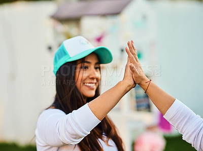 Buy stock photo Shot of a cheerful young woman giving another person a high five outside during the day