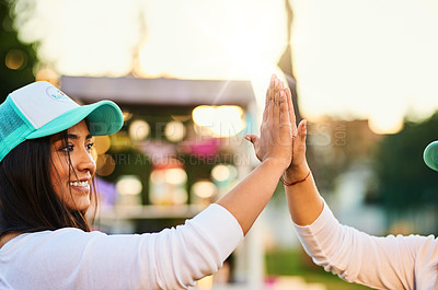 Buy stock photo Shot of a cheerful young woman giving another person a high five outside during the day