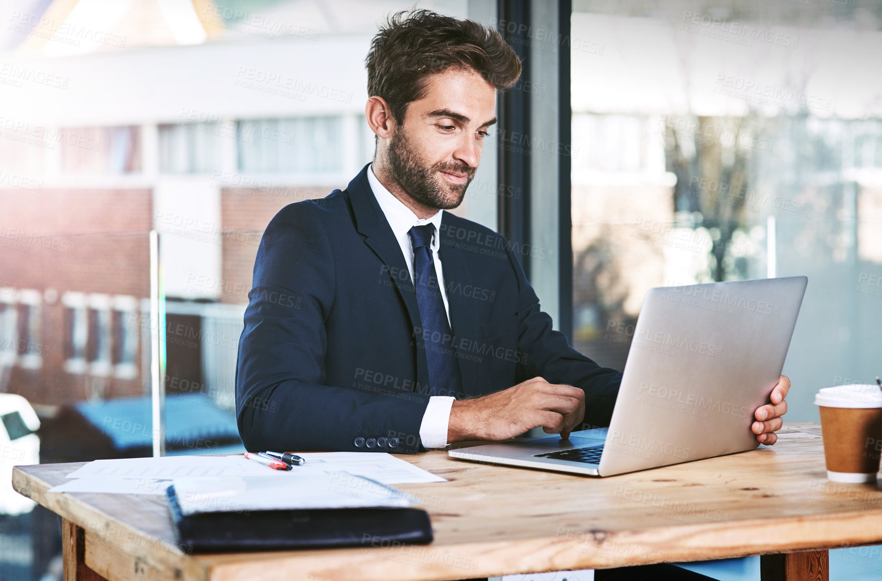 Buy stock photo Cropped shot of a handsome young businessman working on his laptop in the office