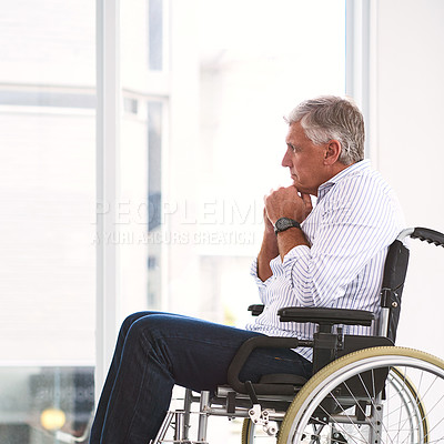 Buy stock photo Shot of a focused mature man sitting in a wheelchair while contemplating inside a clinic