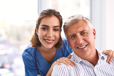 Buy stock photo Portrait of a cheerful young doctor and mature male patient smiling and looking into the camera