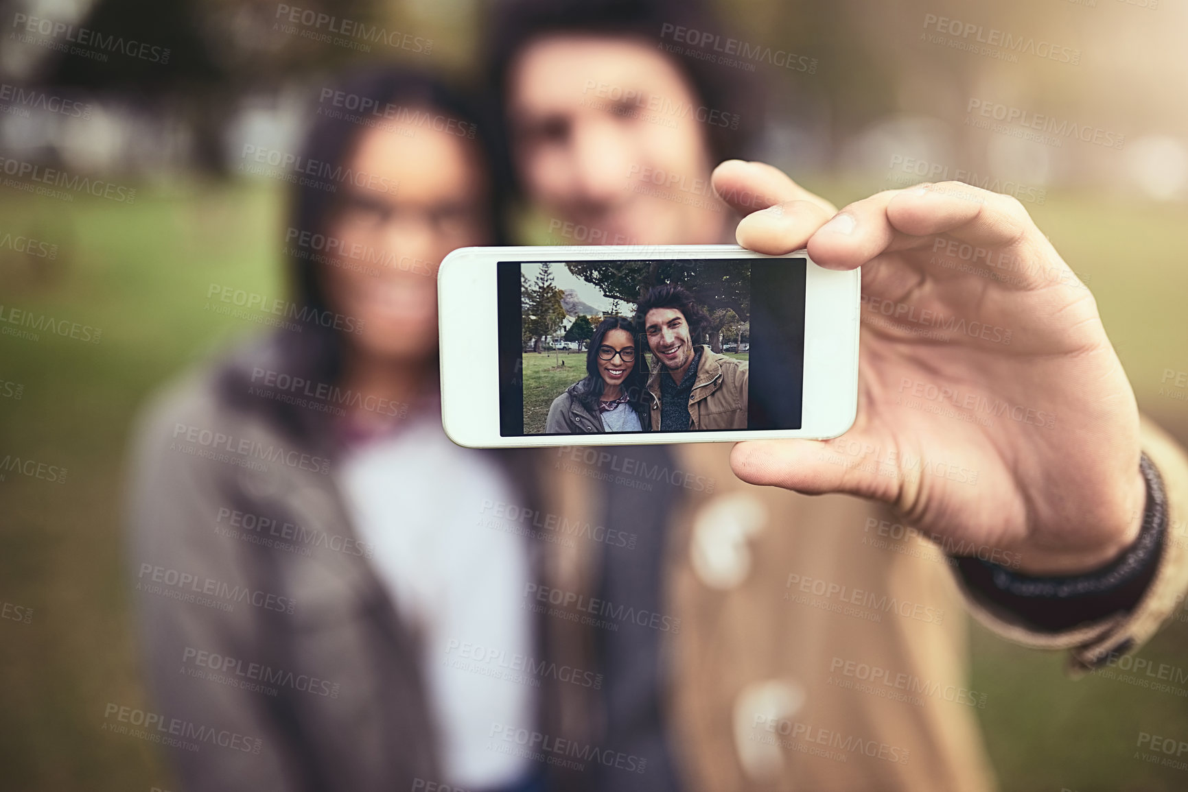 Buy stock photo Shot of a cheerful young couple taking a self portrait together while standing outside in a park