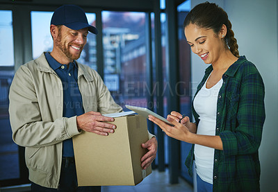 Buy stock photo Shot of a young woman using a digital tablet to sign for a package from a delivery man